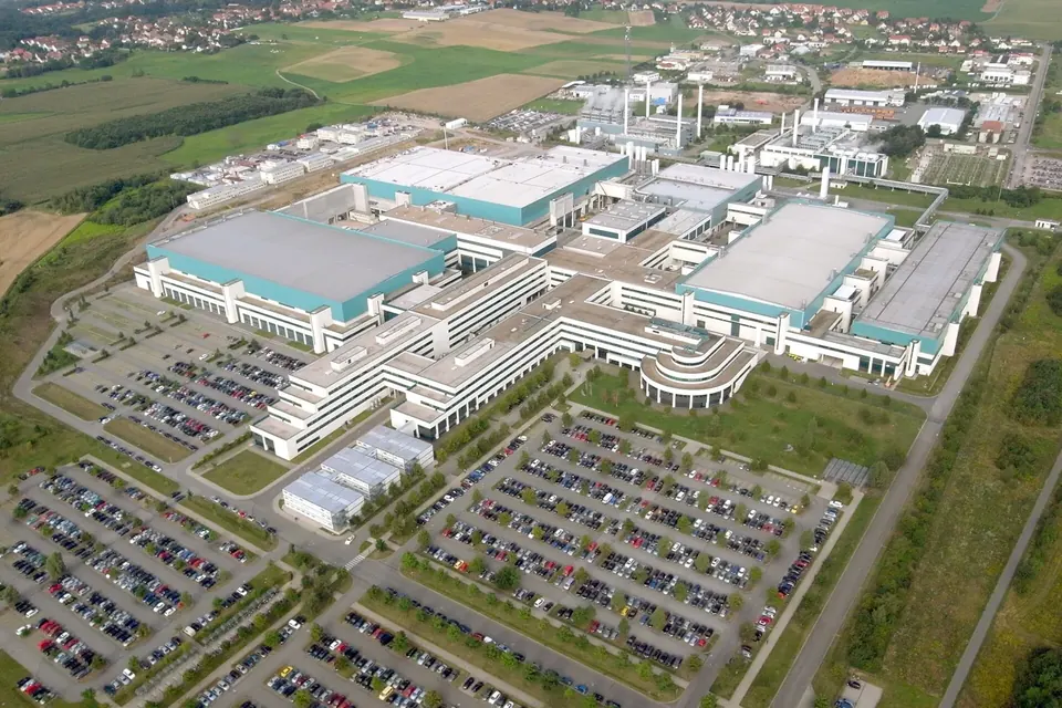 Aerial view of a large semiconductor plant with flat cleanroom buildings, car parks and fields around it