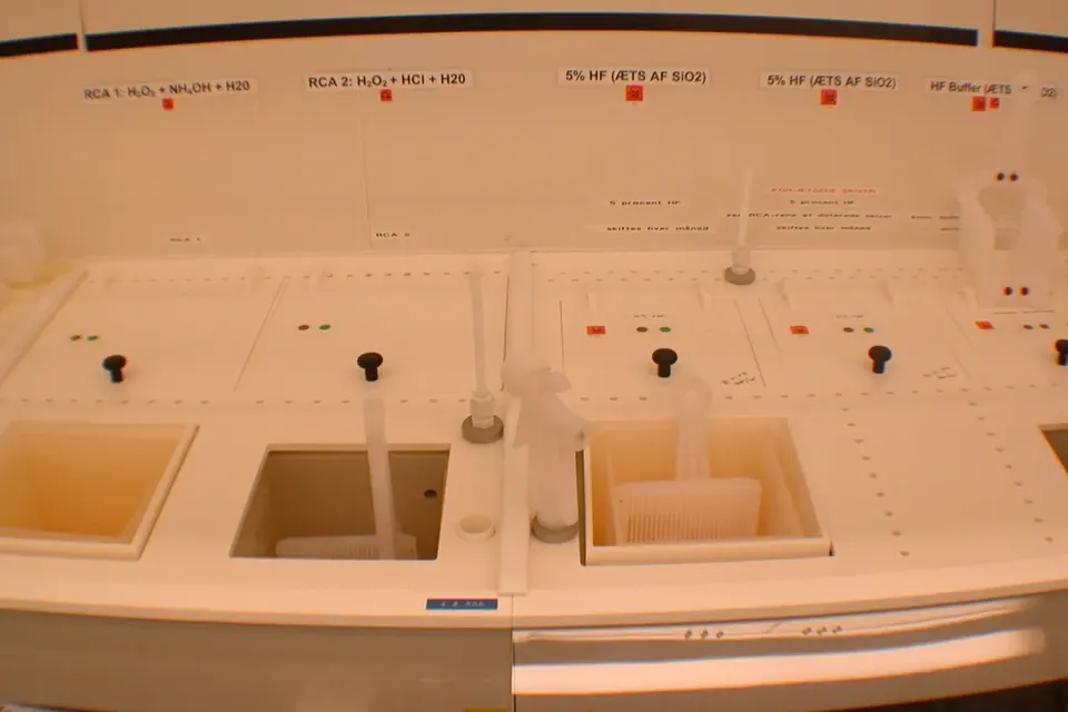 A wet bench in a cleanroom with several baths, labelled above with etching and cleaning solutions such as hydrofluoric acid
